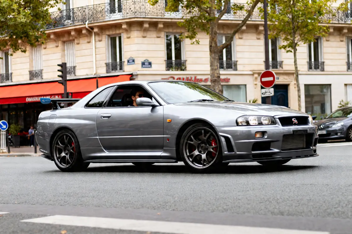 Voiture Nissan GT-R sports car grise roulant en ville près d'un bâtiment haussmannien